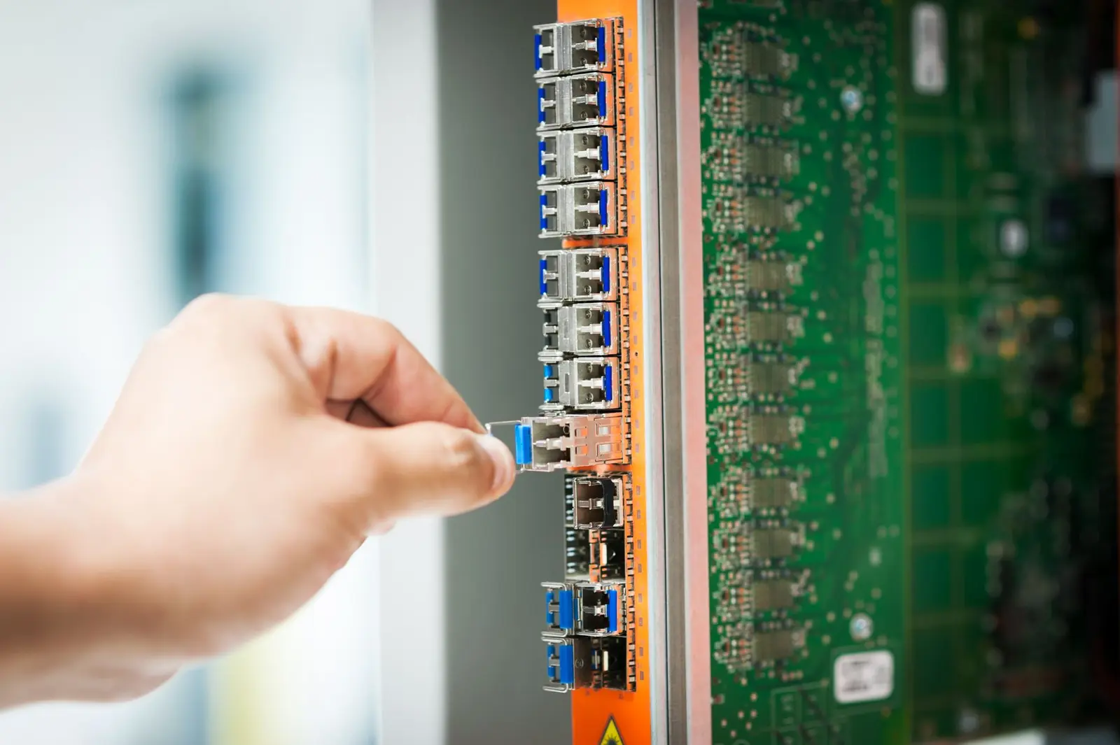 Engineer inserting a fiber transceiver into a network line card.