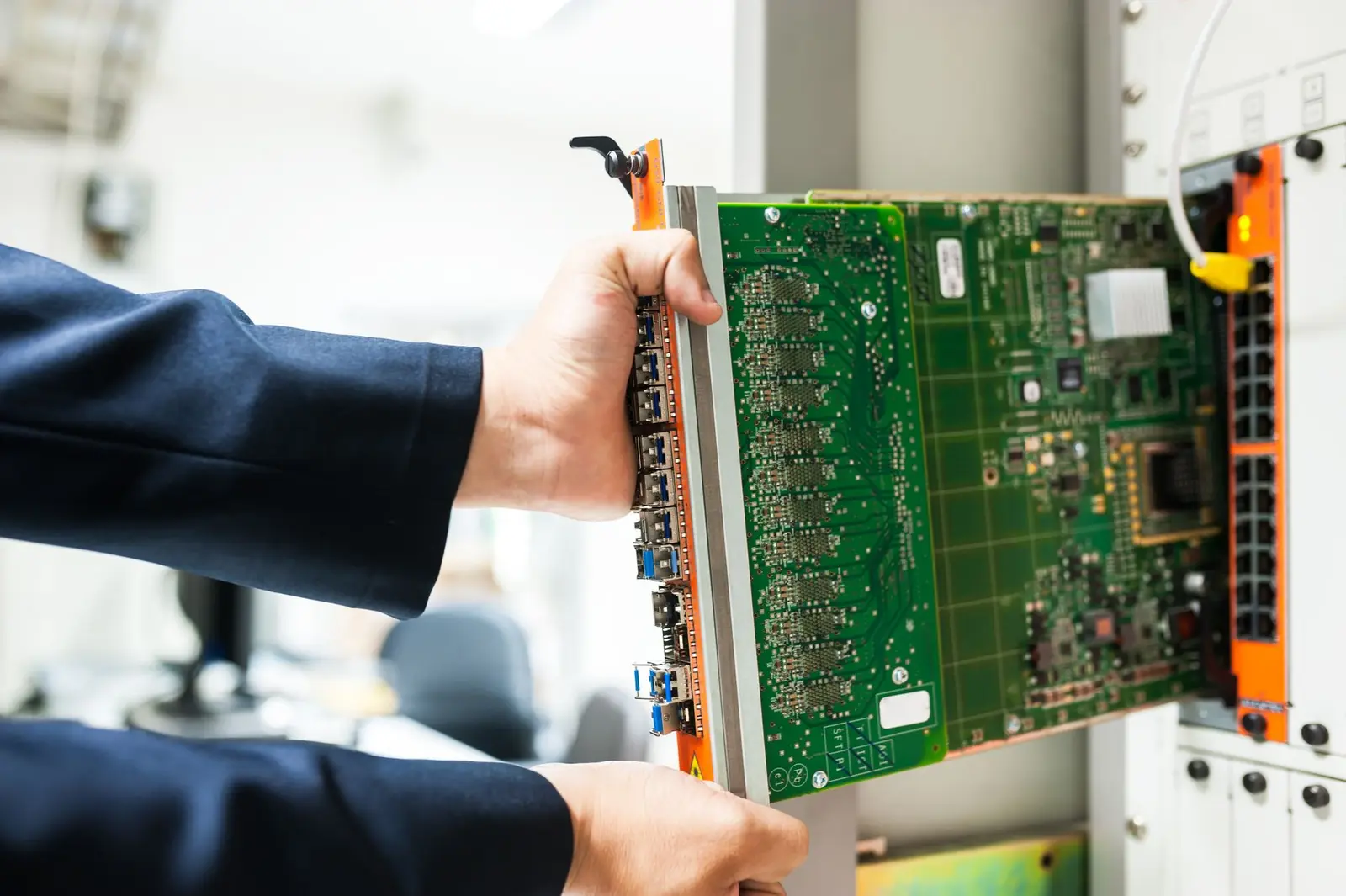 Technician sliding a circuit board into an enterprise server chassis.